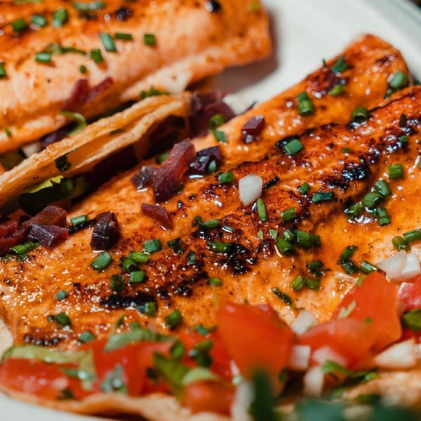 Close-up of two Rene's Mexican Kitchen tacos with grilled meat, chives, and diced tomatoes.