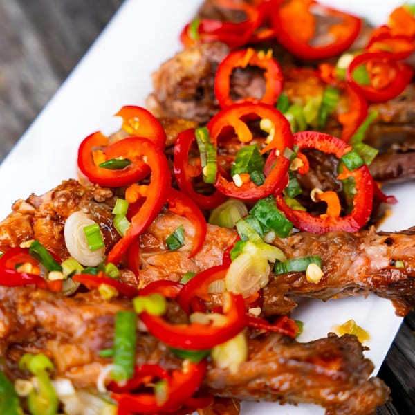 Close-up of Rene's Mexican Kitchen's ribs, garnished with red bell peppers and green onions.