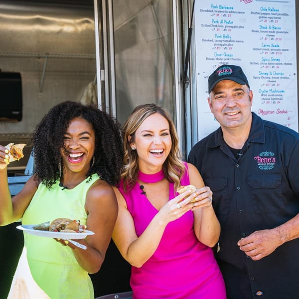 Two women and a man, Rene, smiling and holding Rene's Mexican Kitchen food in front of a food truck menu.