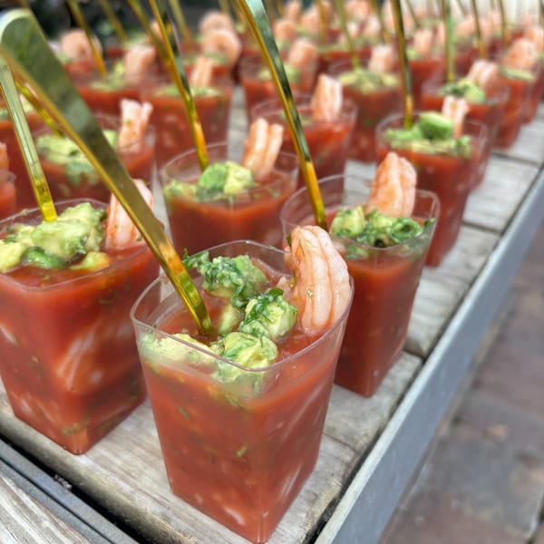 Rows of Rene's Mexican Kitchen shrimp cocktail shooters with avocado and golden spoons.