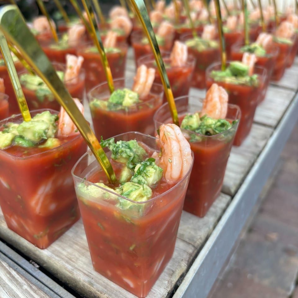 Rows of Rene's Mexican Kitchen shrimp cocktail shooters with avocado and golden spoons.
