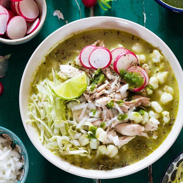 A bowl of Rene's Mexican Kitchen's pozole verde with chicken, hominy, radishes, cabbage, and lime.